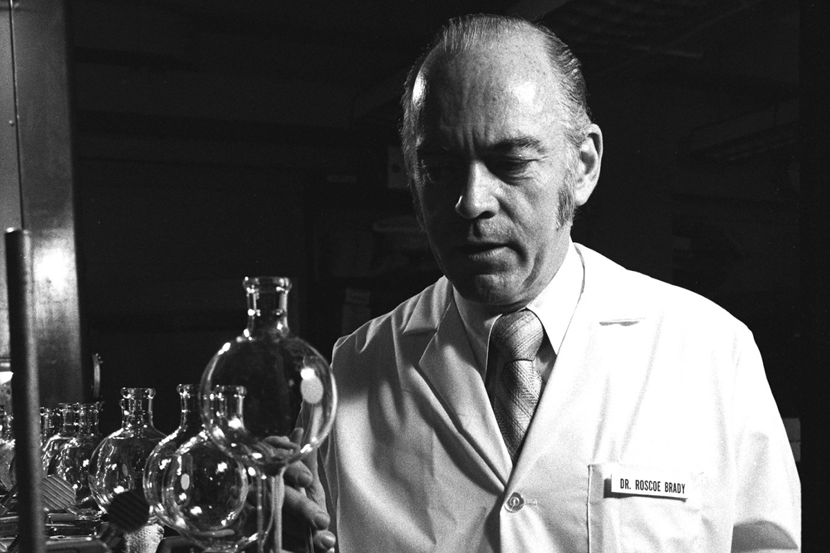 Dr. Roscoe Brady who developed the first enzyme replacement therapy for Gaucher Disease, standing in front of scientific equipment