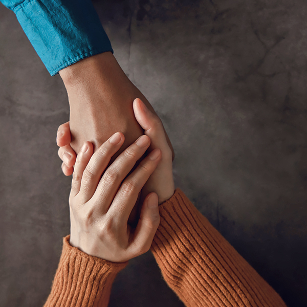 A close-up of someone holding another person's hand in theirs