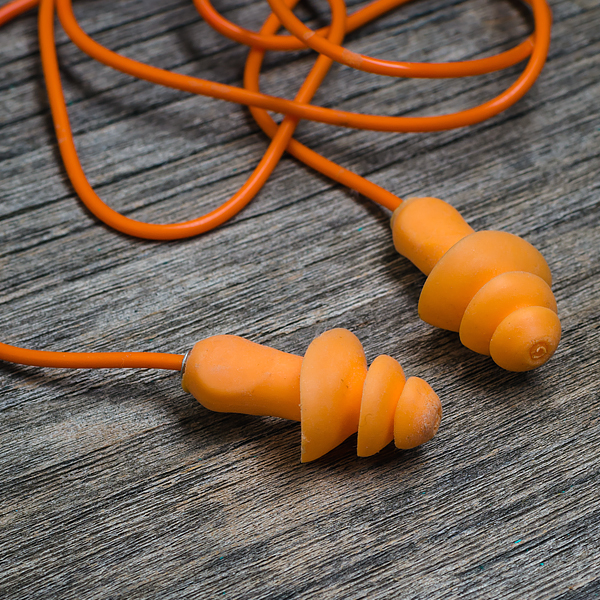 A pair of orange high fidelity earplugs on a wooden background