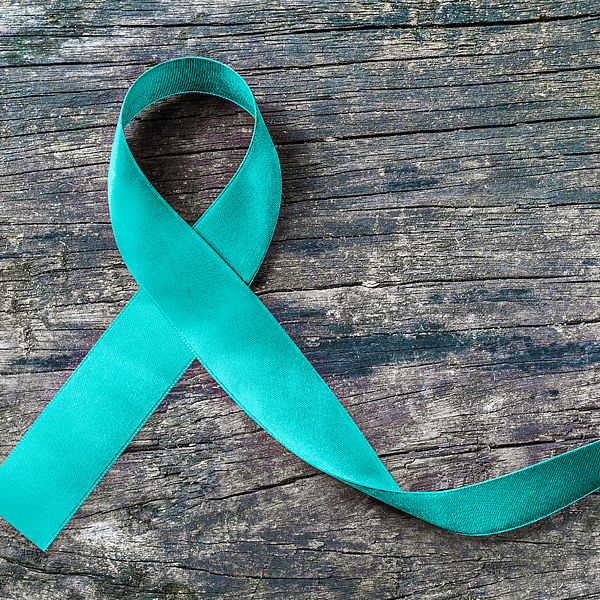 A teal awareness ribbon on a wood surface