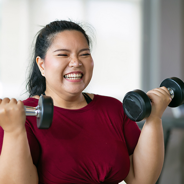 A smiling woman working out with dumbbells