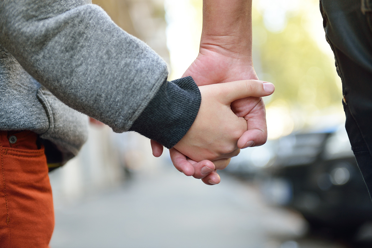 Image of an adult holding a child’s hand