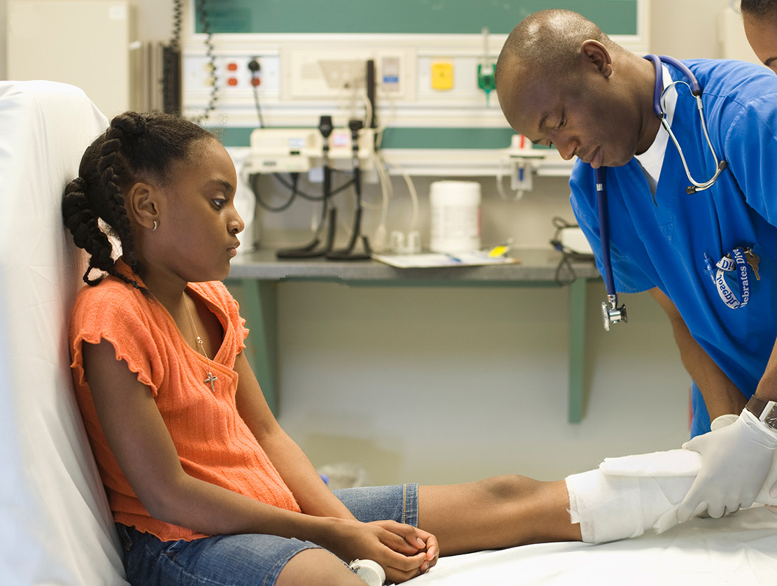 An image of 2 health care workers at a hospital attending to a girl’s leg.