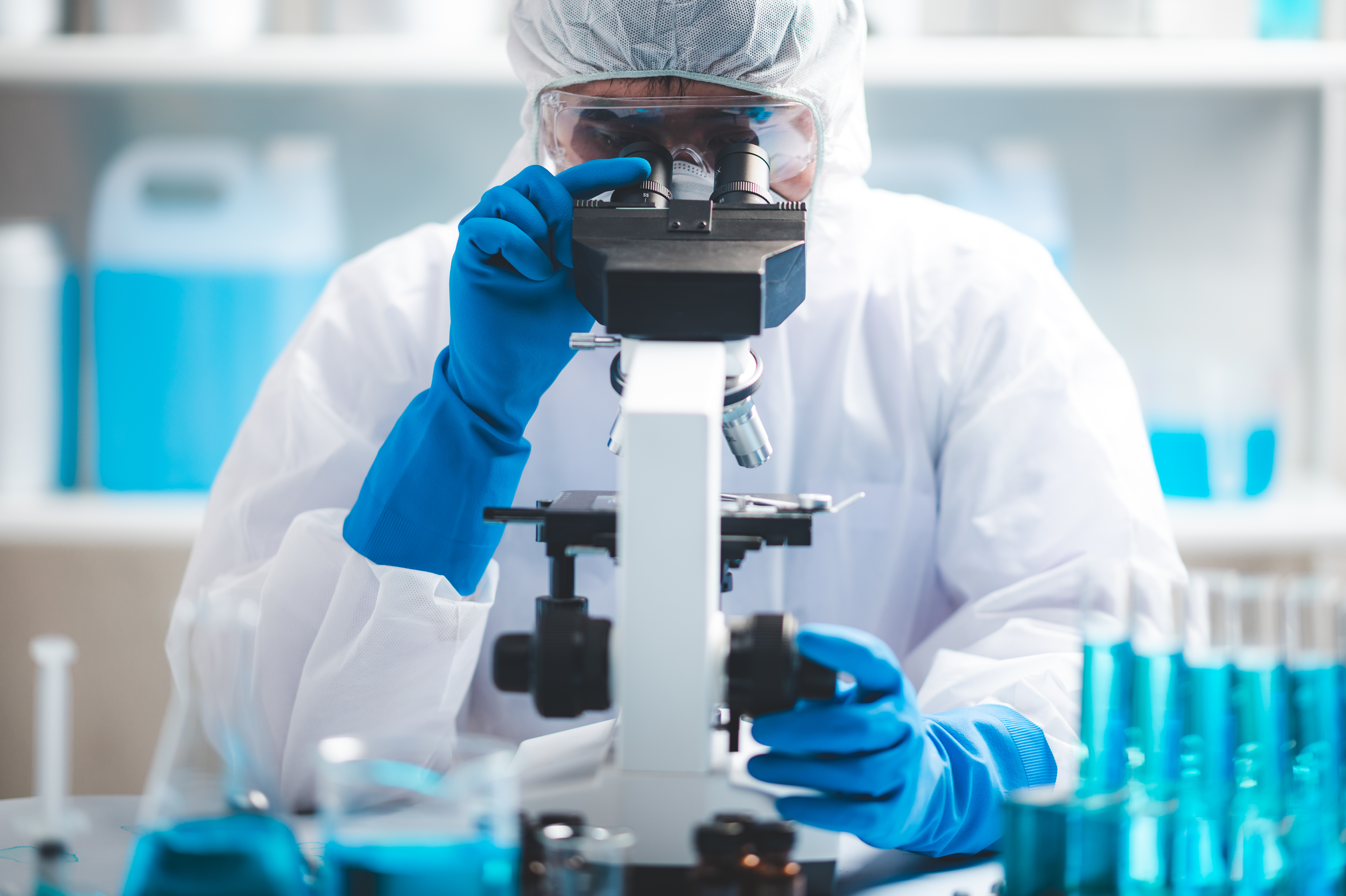 Image of a scientists looking at a sample through a microscope.