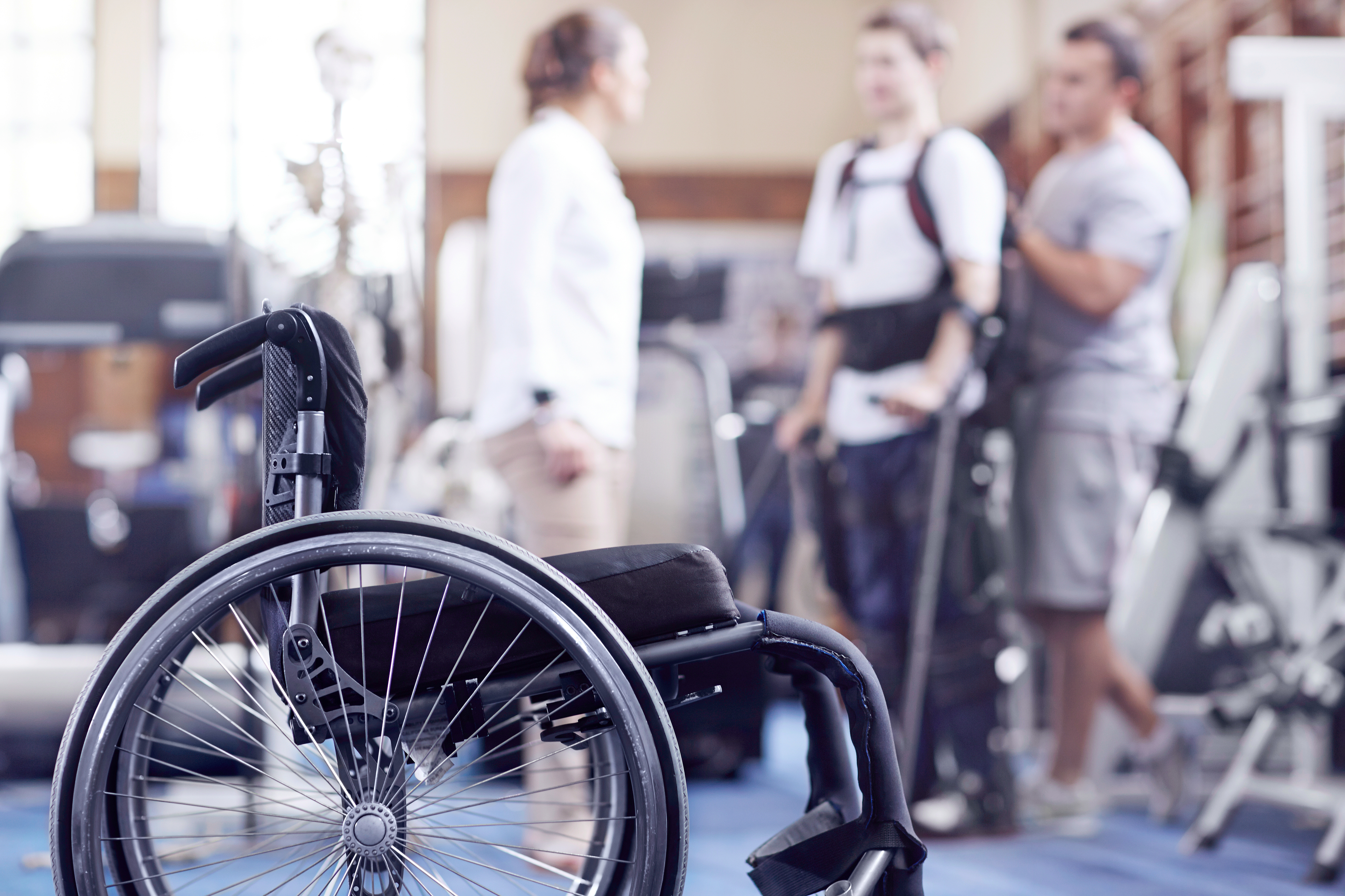 Man receiving physical therapy with wheelchair in foreground.