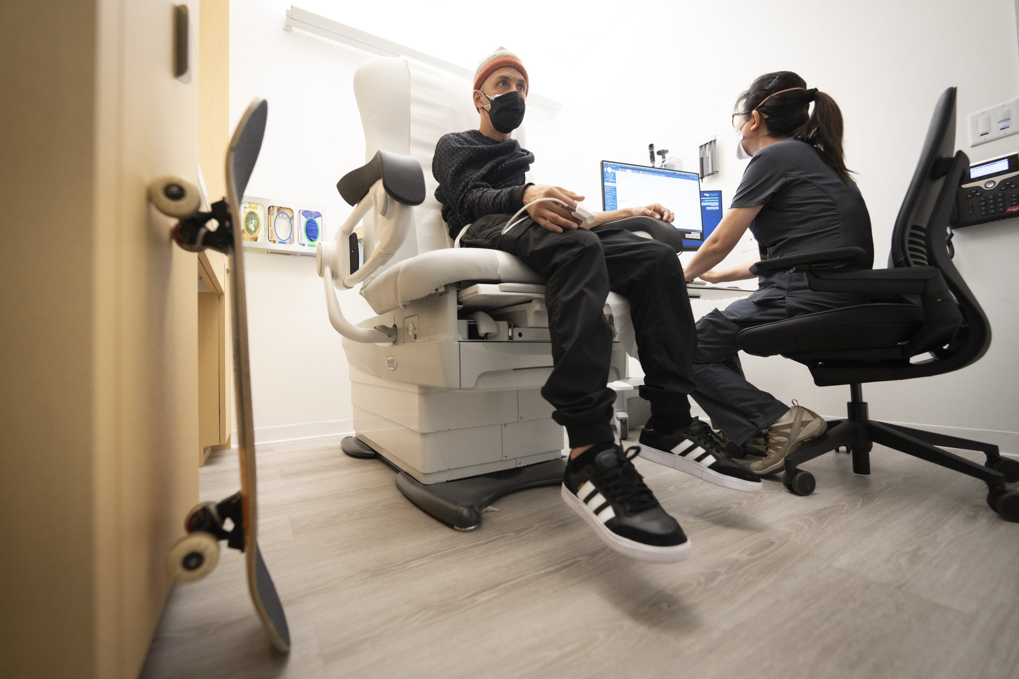 Man in hospital chair getting his vitals monitored by a technician.