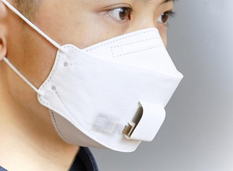 A woman wearing an EBCare smart mask, a paper mask with sensors in the area over the mouth.