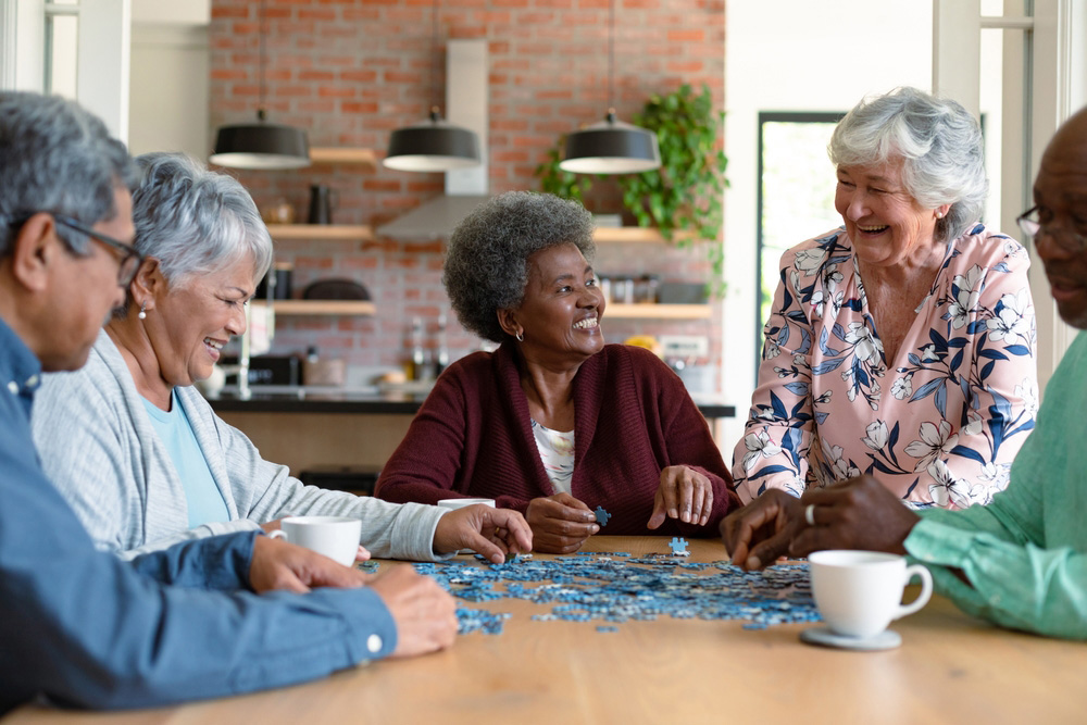 Group of senior male and female friends doing a puzzle together at a table. 