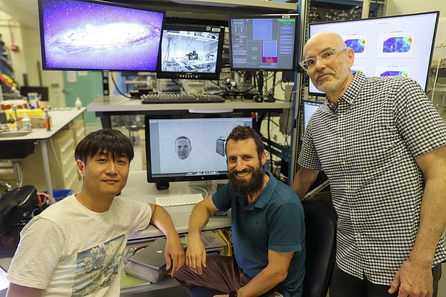 Three male scientist in front of computer monitors