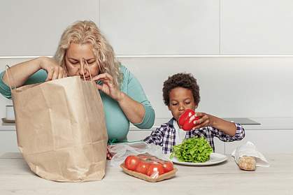 Mom and son taking healthy groceries out of a paper shopping bag.