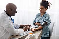 A doctor checking the blood pressure of a pregnant woman.