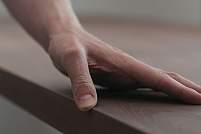 man hand checking toned walnut table surface before applying finish 