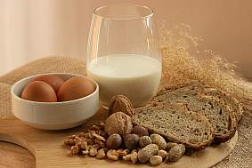  Peanuts, milk, eggs, wheat, cashews, walnuts, and hazelnuts on a wooden tray.