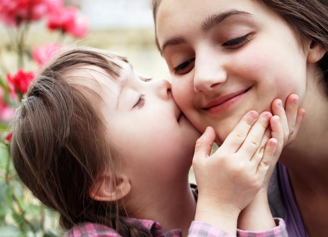 Child with Down Syndrome kissing the cheek of an adult