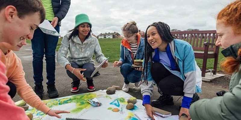 Group of diverse teens outside painting event posters.