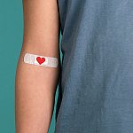 A close-up of an arm with a heart Band-Aid over the inner elbow