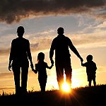 A silhouette of a family holding hands and walking during sunset.