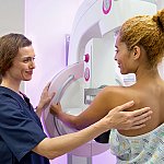 A radiology technologist performing a mammogram on a woman