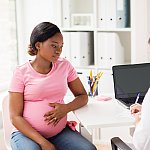 Image of a pregnant person meeting with a doctor.