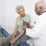 Doctor measuring blood pressure of senior Black woman