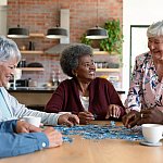 Group of senior male and female friends doing a puzzle together at a table. 