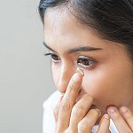 Teen putting a contact in her eye.