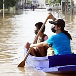 Woman with child paddling a boat in a flooded street