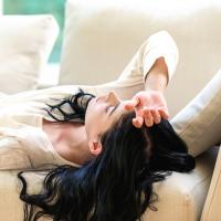 Young woman lying on a sofa with her eyes shut.